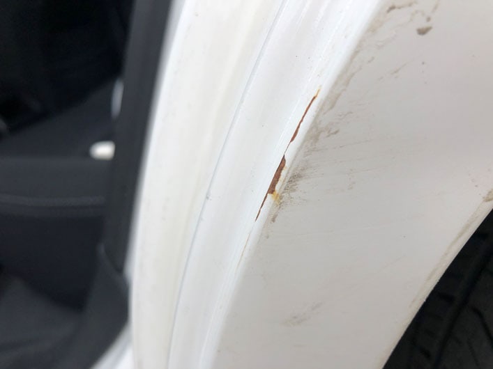 Paint scratch and rust on a white car